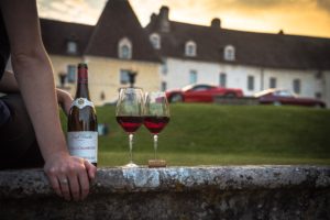 Weingläser und Flasche vor Luxusautos